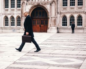 Photo of a man walking past an old, historic building. Gait technology is a way credit card companies can establish your identity in certain situations.