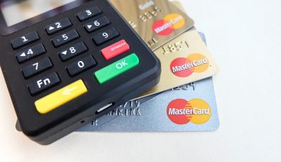 Some Mastercard credit cards and a credit card reader. Mastercard and Visa are postponing their merchant fee increase until 2022.